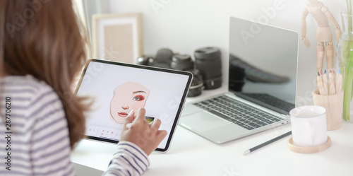 Close-up view of professional designer drawing her project with tablet in modern workplace photo