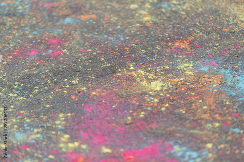 Colored powder paints scattered on the asphalt during the Holi festival.