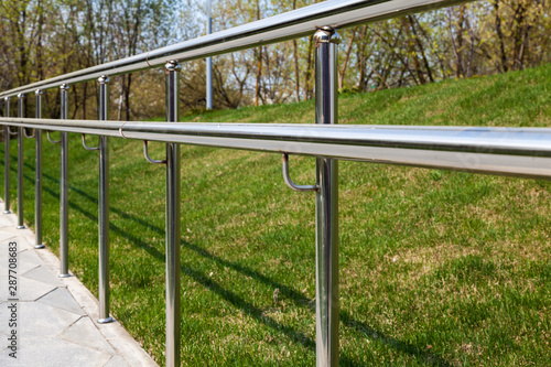 Departing stainless steel fence against a background of green grass