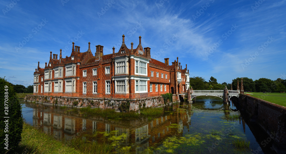 Helmingham Hall with moat bridge and reflections.