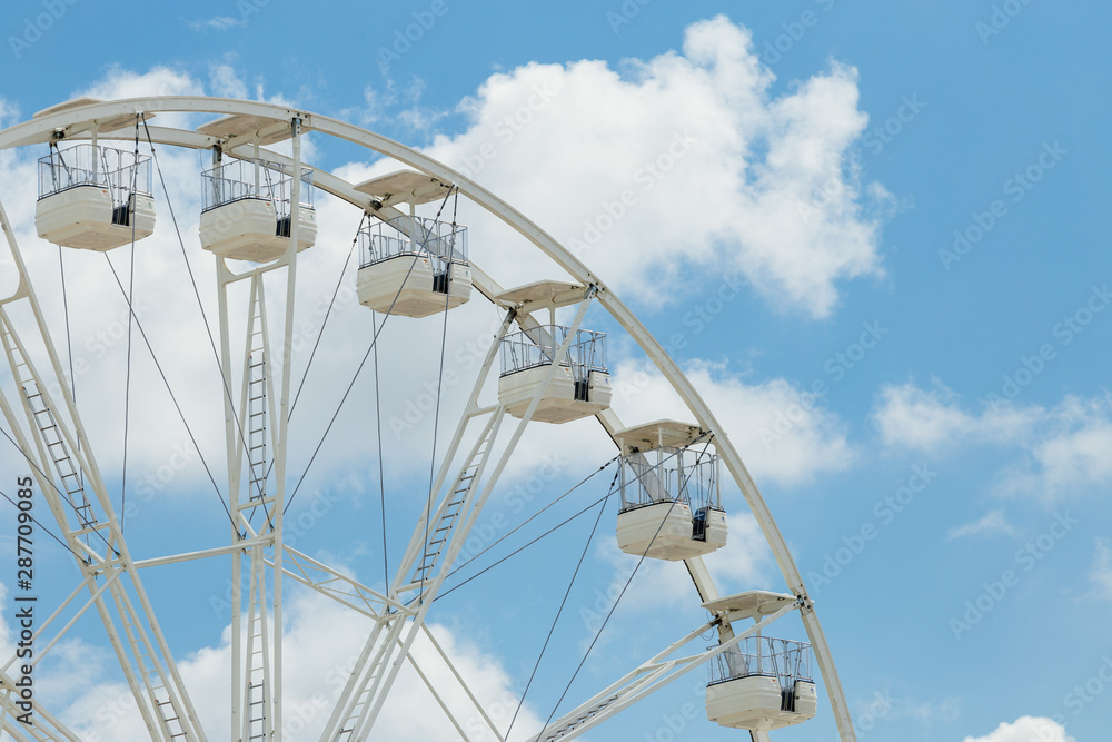 Ferris wheel on the blue cloudy sky. Background concept of happy holidays time.