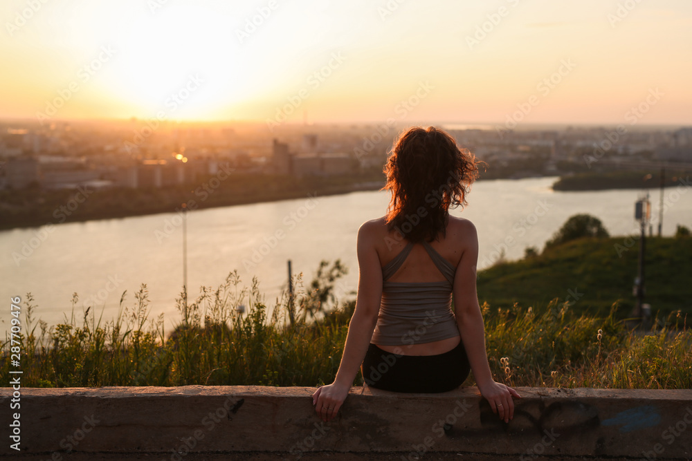 woman in T-shirt sitting in park at sunset,