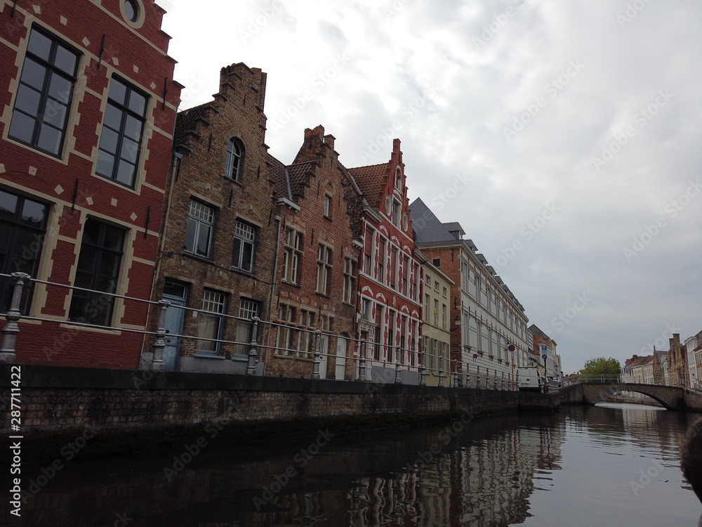Naklejka premium Bruges, Belgium - May 2019: View of the water channel in the city center. Boat trip along the water canals of the city.