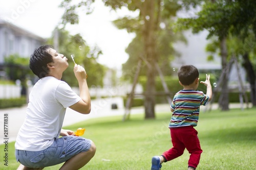 Father and son making soap bubbles in the park of village. Concept of friendly family.