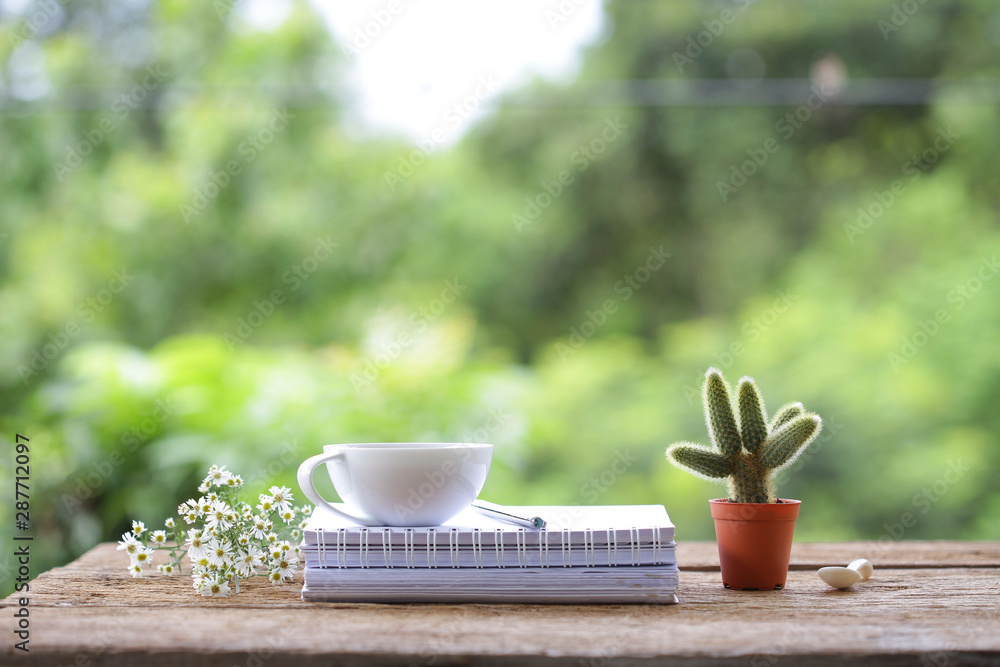 Whitecup of coffee  and small Cactus with on wooden table with diary notebooks