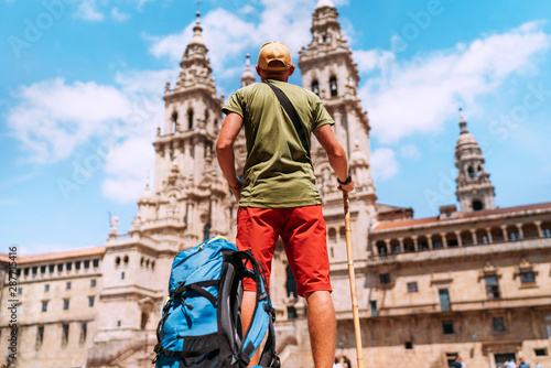 Young backpacker man pilgrim standing on the Obradeiro square (plaza) - the main square in Santiago de Compostela as a end of his Camino de Santiago pilgrimage.