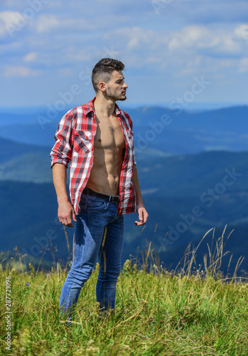 Hiking concept. Strong hiker muscular torso. Athlete muscular guy relax mountains. Power of nature. Man unbuttoned shirt stand top mountain landscape background. Muscular tourist walk mountain hill