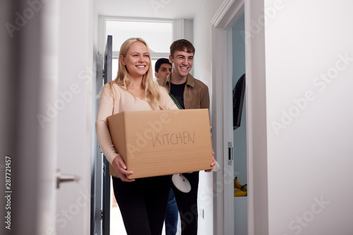 Group Of College Student Carrying Boxes Moving Into Accommodation Together photo
