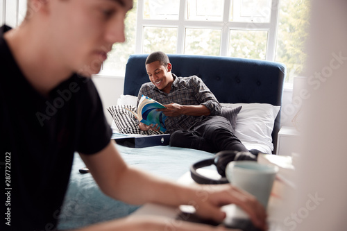 Two Male College Students In Shared House Bedroom Studying Together