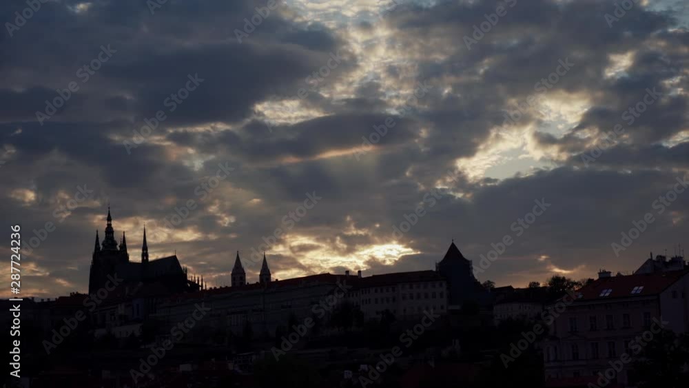 silhouette of a wall with towers, beautiful sunset, golden rays of sun peeping through thick gray-blue clouds