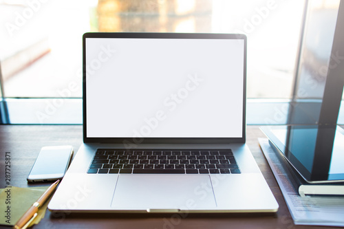 Workplace with open modern pc laptop computer with mock up copy space screen background for promotional content. Notebook with mobile phone, touch pad lying on a wooden table in coworking space