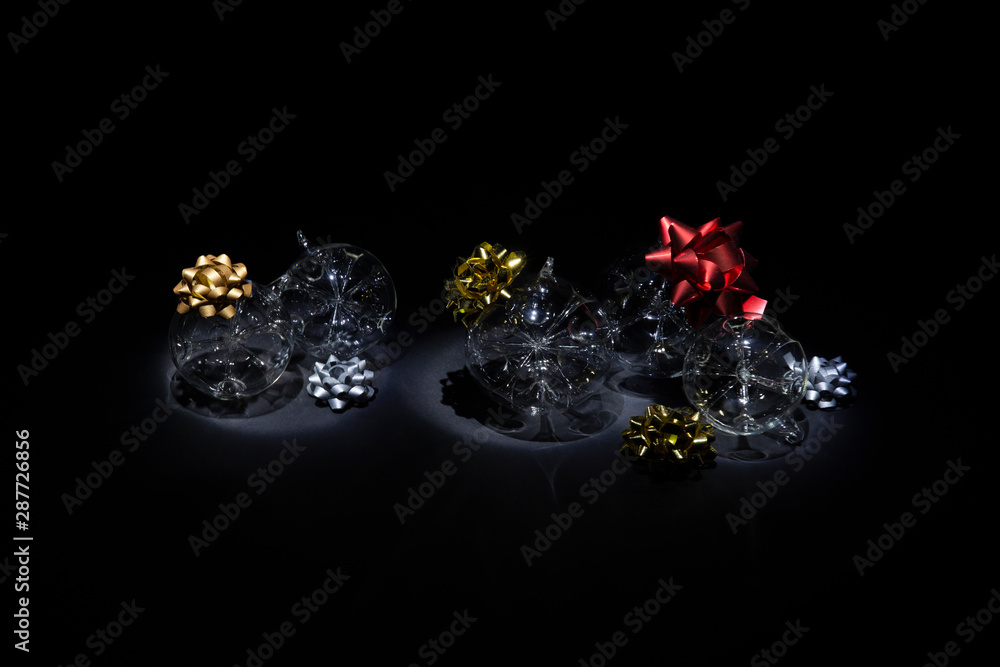 Fototapeta premium Transparent glass Christmas balls with colorful ribbons on black background