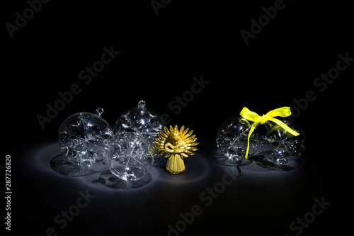 Transparent glass Christmas balls and straw angel on black background