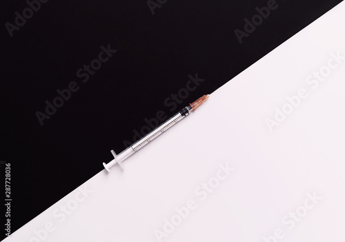 Empty syringe on black and white background. Flat lay style. Copy space. Medical treatment and women beauty concept.