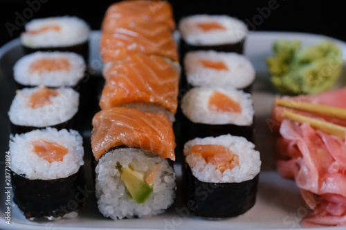 Sushi roll with seafood and soy sauce, wasabi and ginger. Sushi roll with salmon on a black background.