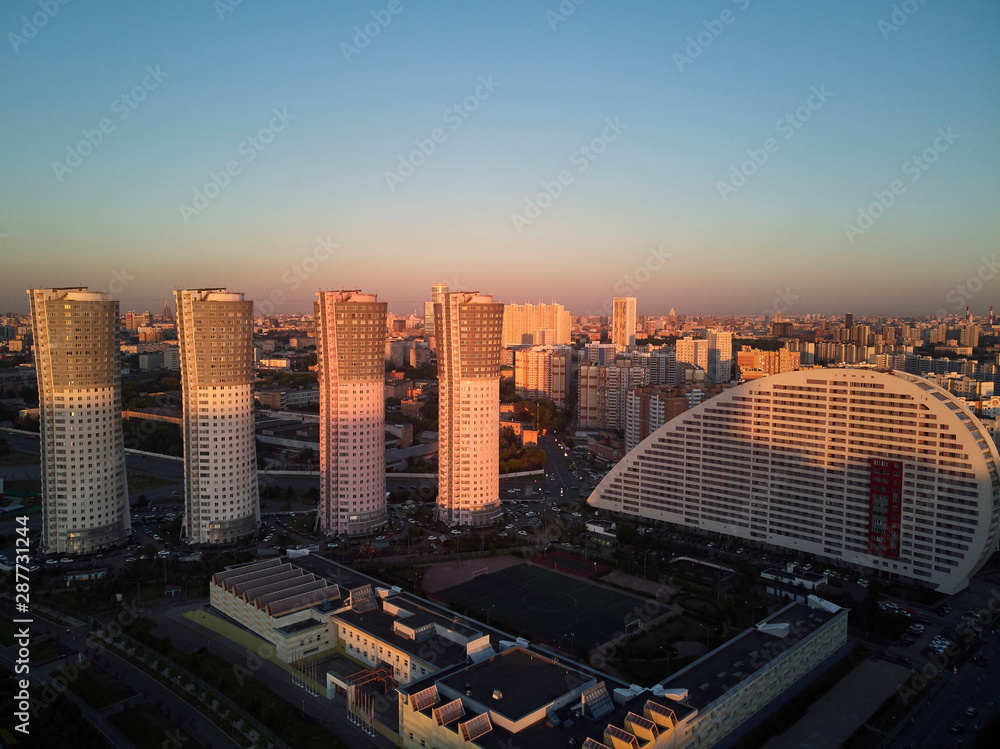 Obraz premium Cityscape with four high-rise residential buildings and city blocks in the evening. Aerial view