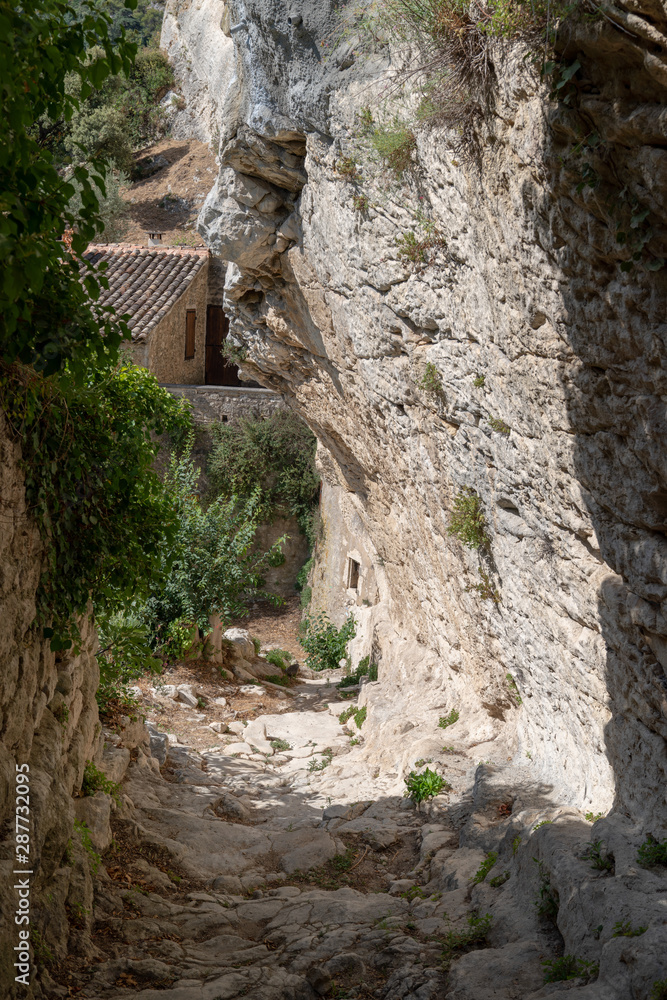 alley street cut into the rock of the mountain with houses in hilltop village Oppede Le Vieux in Provence France