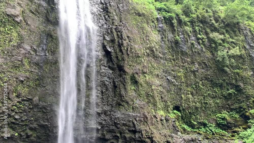 Beautiful waterfall in Hawaii with lagoon. Hanakapi'ai falls on Kauai, Hawaii, near the Na'Pali coast national park. Shot is tilting upwards.