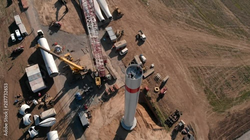 Building process of wind energy power tower mill, under construction. Assembling tower, column, pillar. Green, clean, renewable energy. Aerial footage.