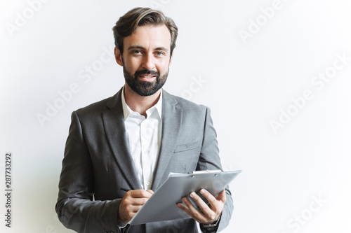 Image closeup of smart confident businessman holding clipboard and writing down notes while working in office