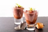 Healthy food concept Chia seeds, chocolate milk pudding with goji and dried walnuts in small Glass on black slate board background