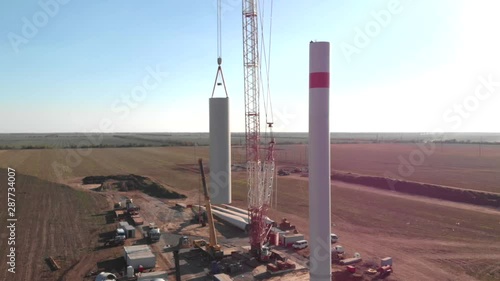 Building process of wind energy power tower mill, under construction. Assembling tower, column, pillar. Green, clean, renewable energy. Aerial footage.
