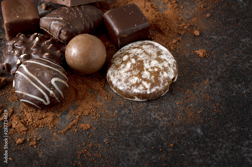 chocolate, cookies and pralines on a dark slate background with copy space