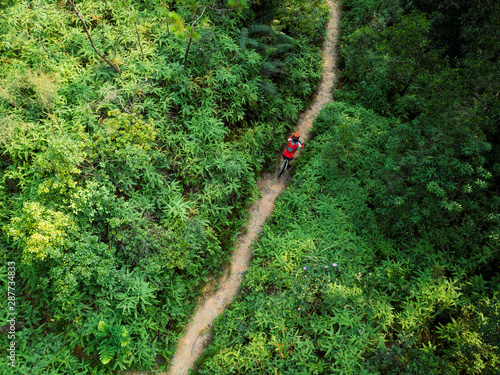Canvas Print Aerial view of cross country biking woman cyclist riding mountain bike on tropic