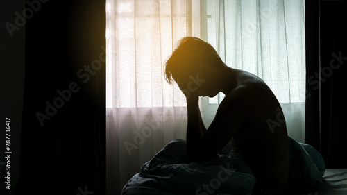 Depressed Man sitting head in hands on the bed in the dark bedroom , Stress, depression, Bipolar disorder,  concept photo