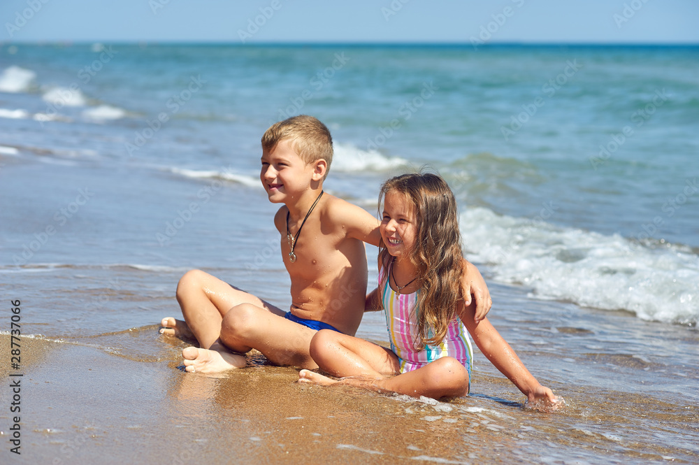 Cheerful children relax on the sea coast . Children's summer vacation