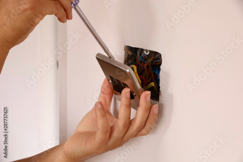A female electrician fitting a light switch