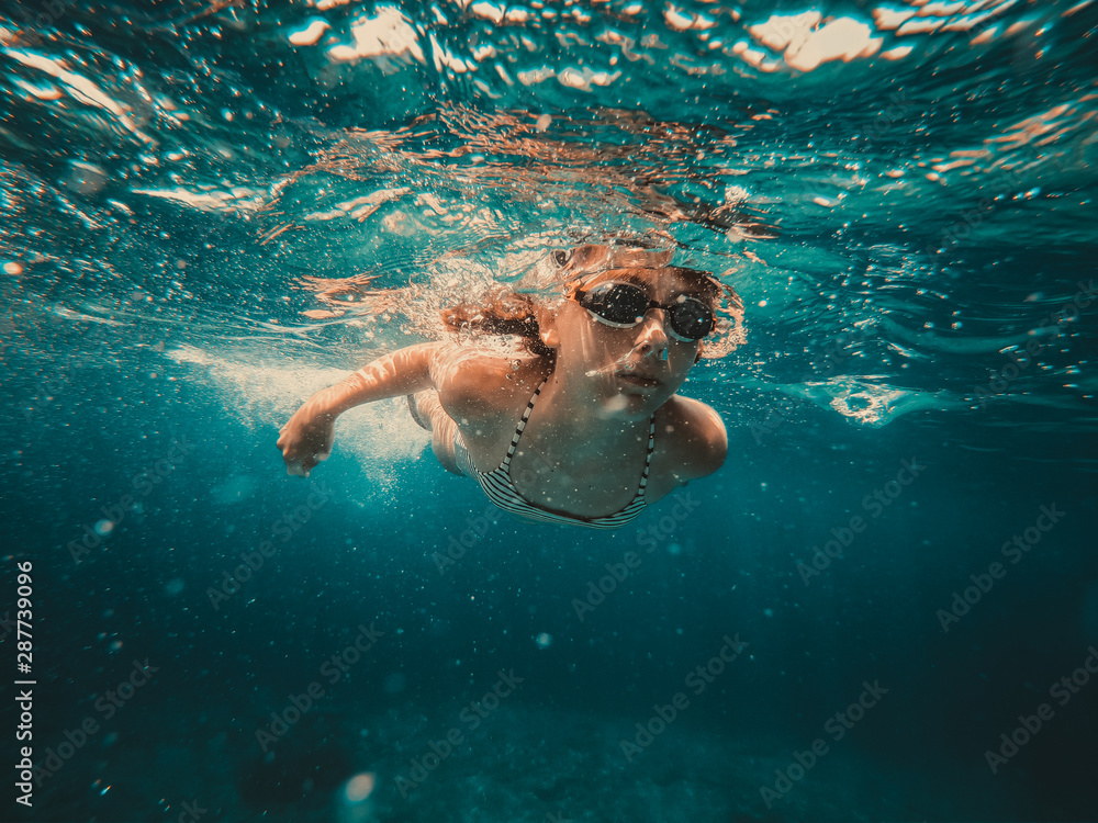 Underwater photo of girl swimming in the sea