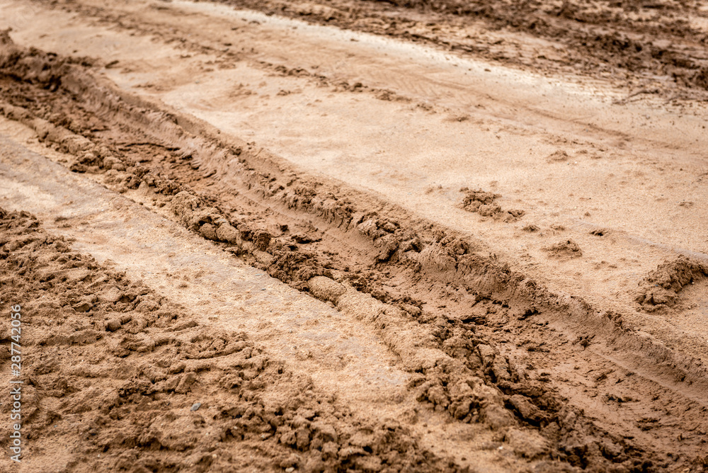 Tracks of car tires on a wet, swampy road with brown water. Country dirt road with paddles after rain Tracks of car tires on a wet, swampy road with brown water. Country dirt road with paddles after rain