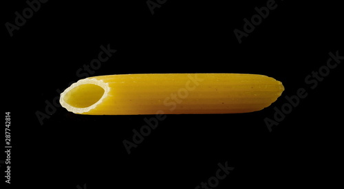 Penne rigate pasta, single, one noodle isolated on black background