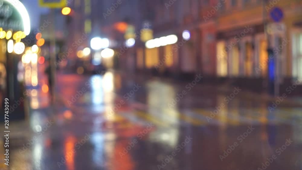 Lights of the night city. Rain, light from windows and cars is reflected on wet asphalt. The movement of multi-colored highlights and spots. Lights of the night city. Rain, light from windows and cars is reflected on wet asphalt. The movement of multi-colored highlights and spots.