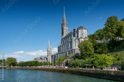 View of the side of the Sanctuary of Lourdes by the river Ousse, in the Pyrenees Mountains (France).