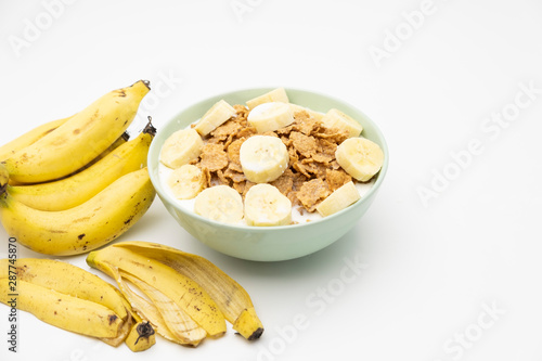 Cereal flake with pieces of banana fruits slice in the blue bowl isolated on white background