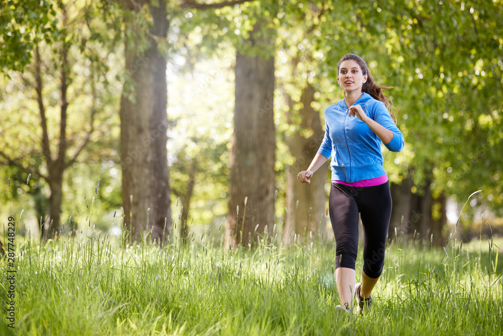 Young Woman Exercising Running Through Countryside Field Young Woman Exercising Running Through Countryside Field