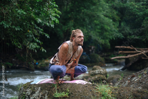 Yoga practice and meditation in nature. Man practicing near river