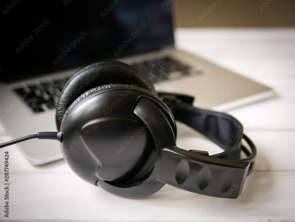 White wooden working desk with notebook and old headphones. Shallow depth of field. White wooden working desk with notebook and old headphones. Shallow depth of field.