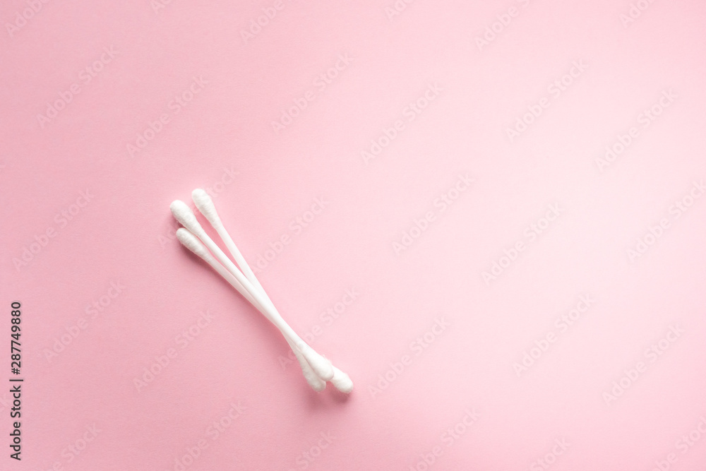 Cotton buds for cleaning ears on a pink background lie diagonally. Cotton buds for cleaning ears on a pink background lie diagonally.