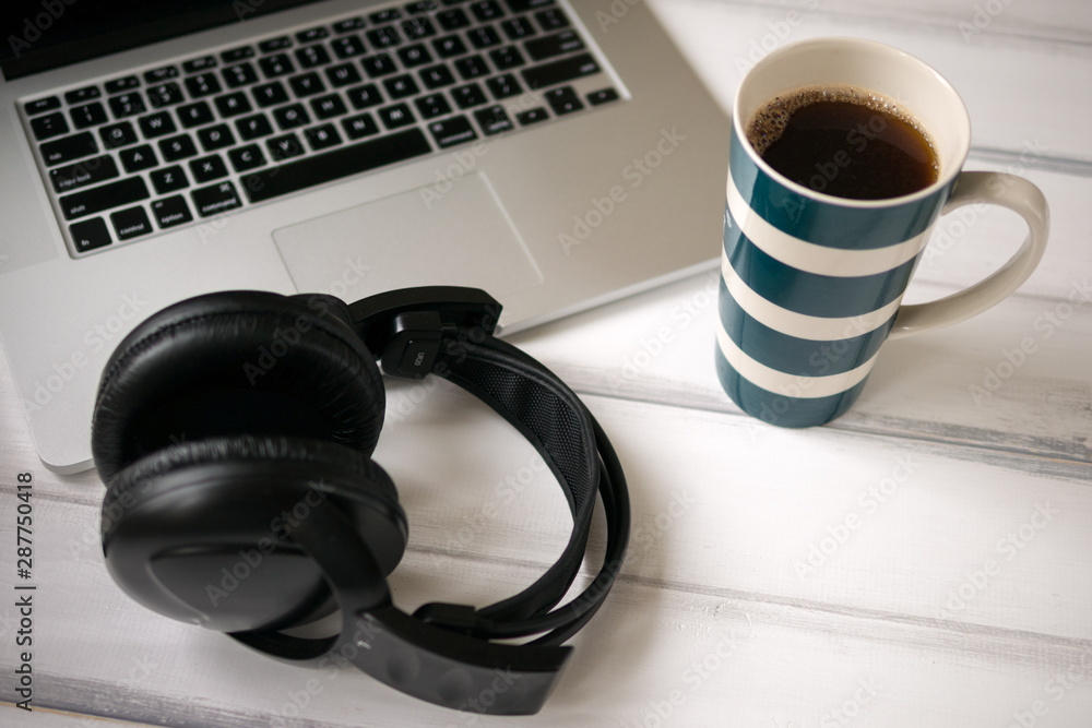 White wooden working desk with laptop, headphones and large mug of coffee. White wooden working desk with laptop, headphones and large mug of coffee.