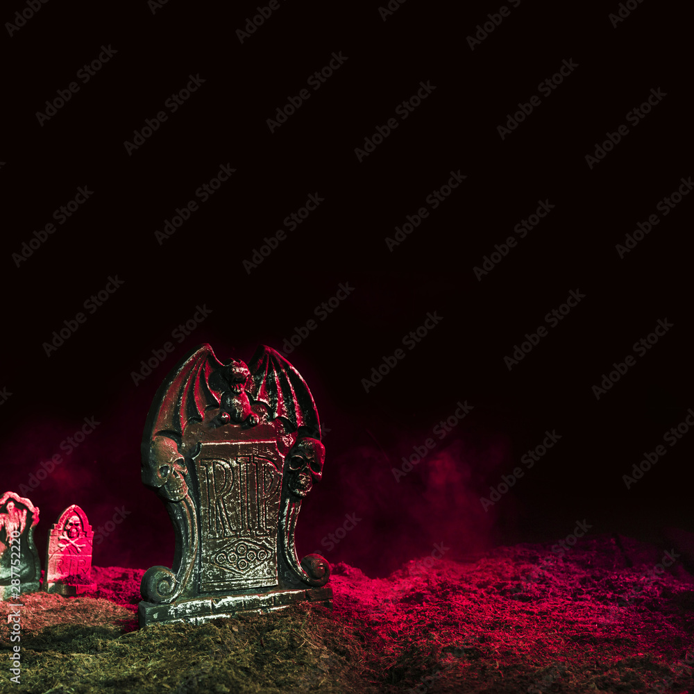Headstones illuminated by pink light onÂ ground