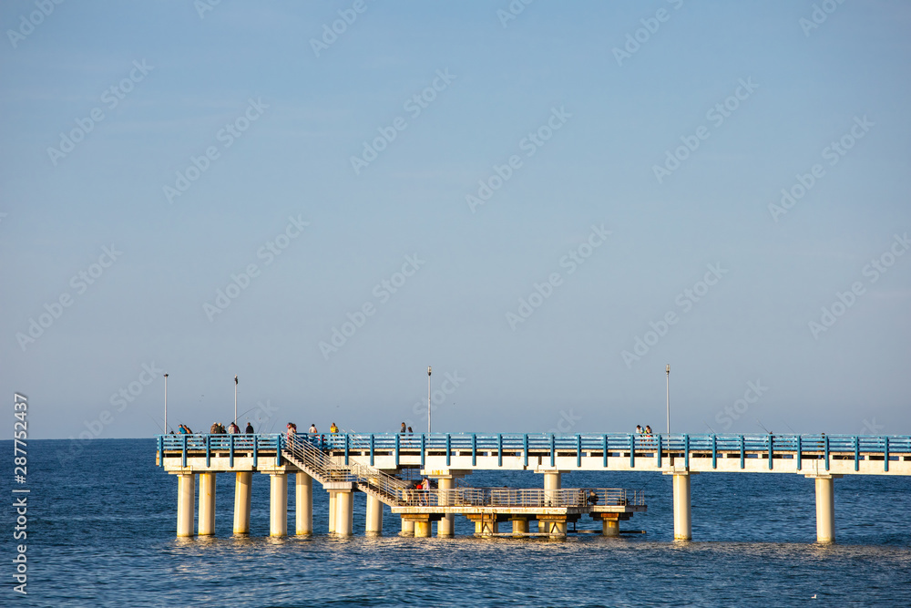 tourists walk on the pier near the sea