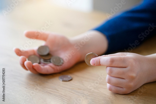 Kid hand holding pound coins on wooden table, Kid learning counting and how different about money coins, Children learning about financial responsibility or planning savings concept.