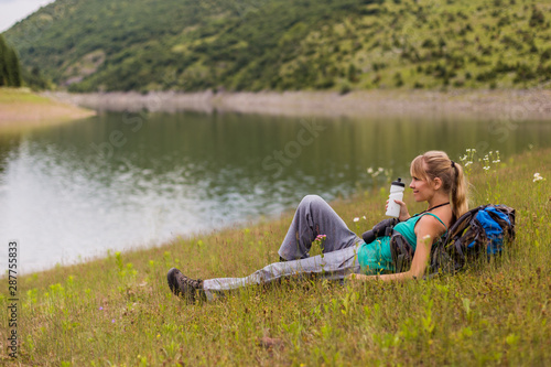 Woman hiker drinking water while spending time in the nature.	