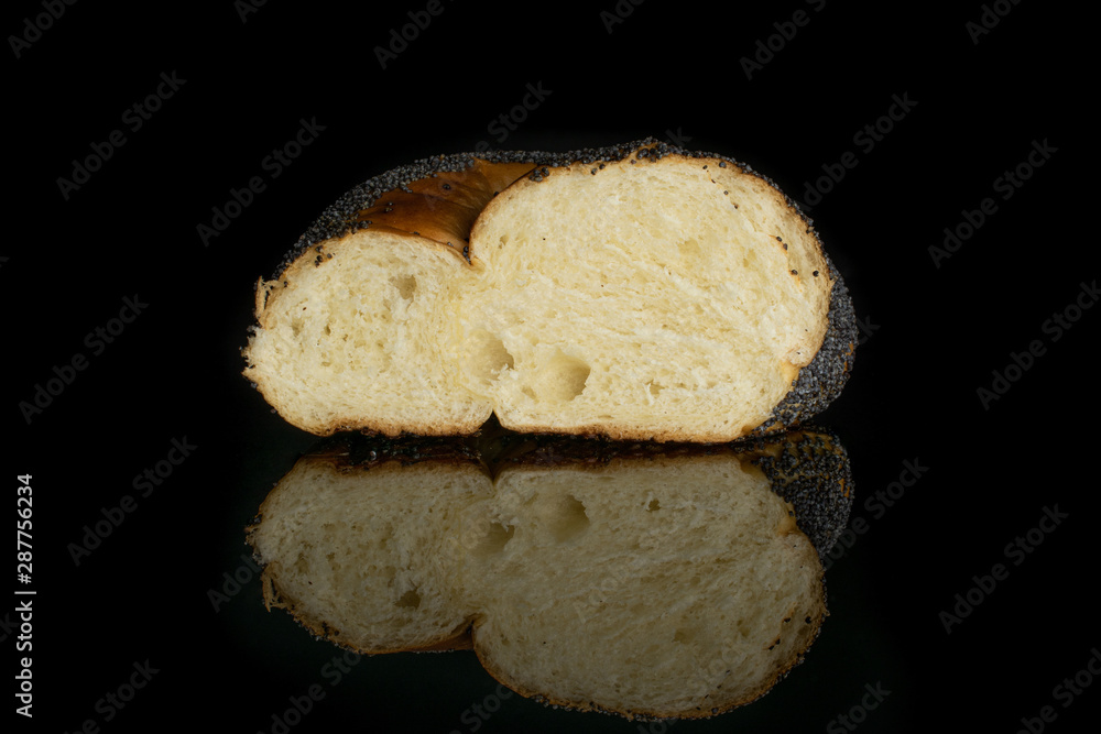 One half of twisted poppy seed bun isolated on black glass One half of twisted poppy seed bun isolated on black glass