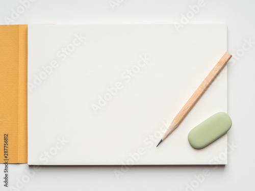 Blank page of sketchbook, pencil and eraser on white background. Flat layout