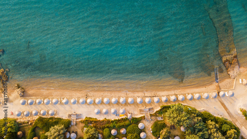 Aerial top view of blue color sea and sandy beach with wooden sunshades on the beach