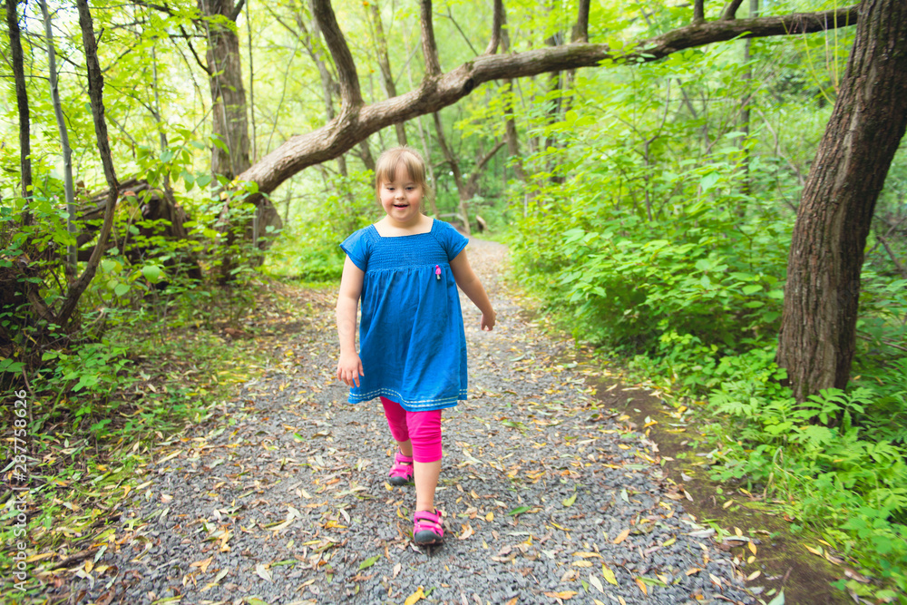 A portrait of trisomie 21 child girl outside having fun on a park A portrait of trisomie 21 child girl outside having fun on a park